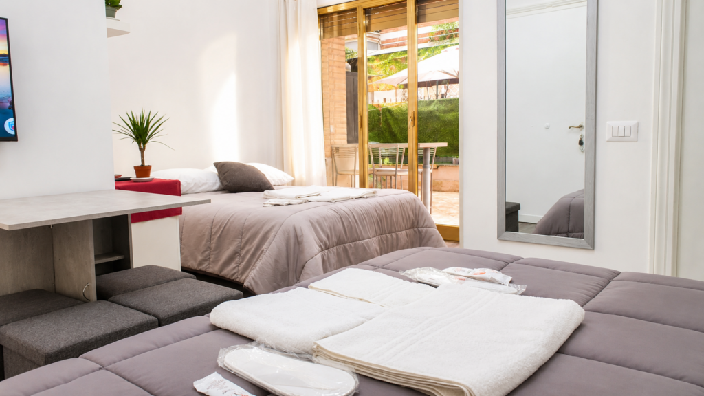 Vista dal letto principale di Aurelia Garden Stay sul divano trasformato in letto e sul giardino privato.