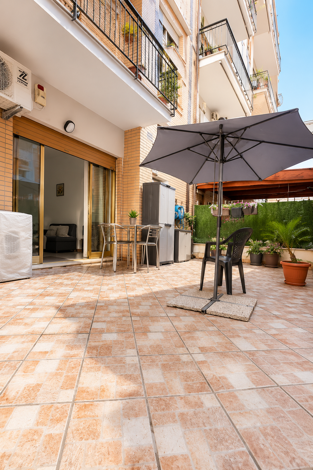 Giardino esterno pavimentato di Aurelia Garden Stay a Roma con ombrellone e penisola per pranzare all'aperto vicino all'Ergife.